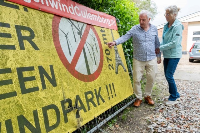 Los Van Weelden ante uno de los carteles contra el parque eólico que colocaron en la localidad de Colemburg y que ahora guardan en su jardín. Laia Ros