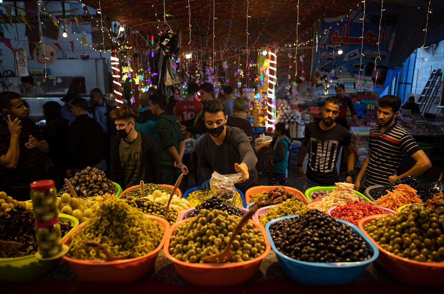 Un vendedor palestino se protege con mascarilla mientras vende pepinillos en el mercado de Zawiya durante un día de Ramadán en Gaza